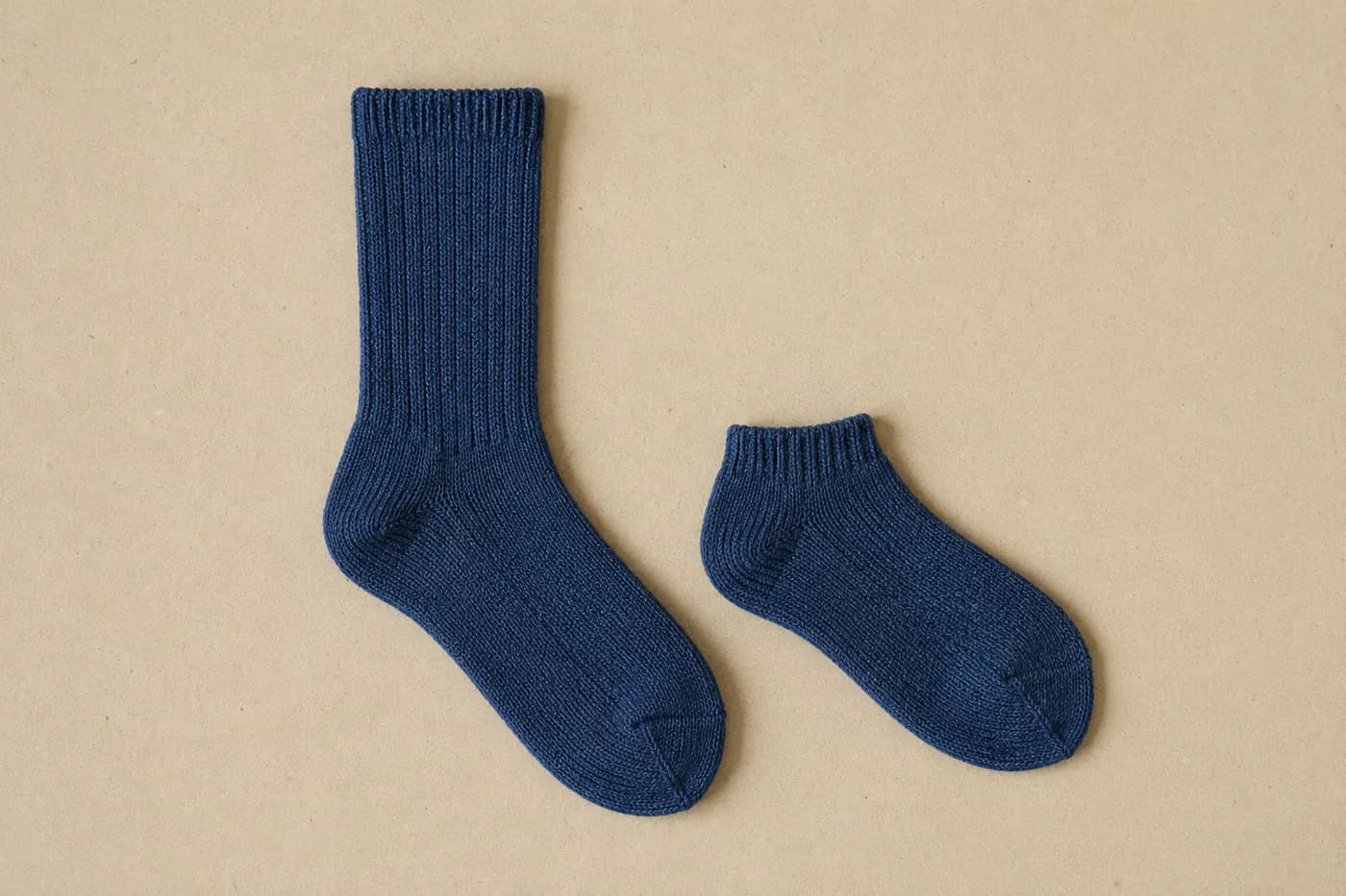 Two navy socks of clearly different lengths laid flat side by side
