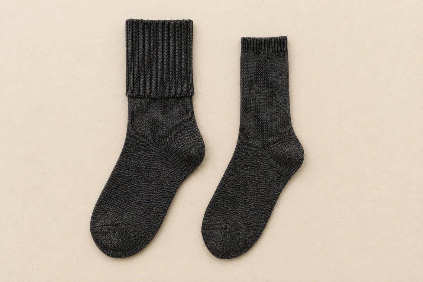 Two charcoal socks of the same length side by side, one with a wide thick cuff and one with a narrow thin cuff