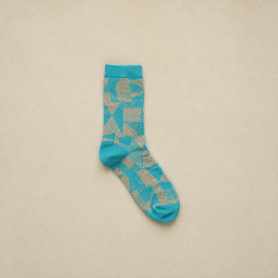 One lone turquoise patterned sock laid flat alone on paper